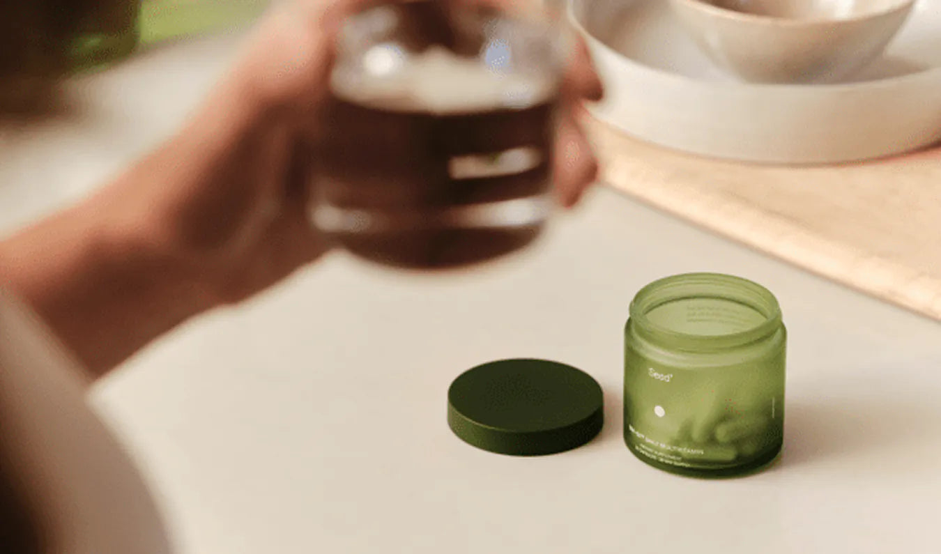 Seed Daily Multivitamin jar with packaging and a hand holding a supplement capsule.
